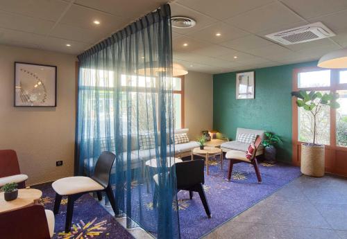 a waiting room with chairs and a table and a couch at B&B HOTEL Saint-Witz Roissy in Saint-Witz