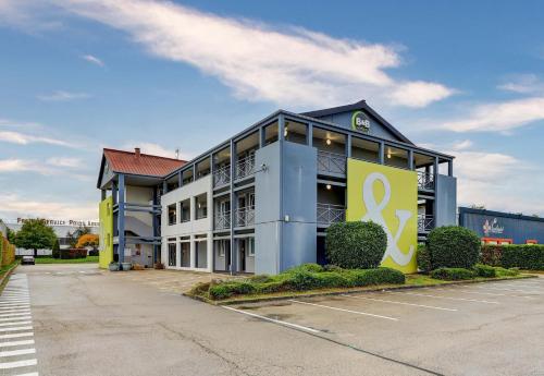 a large building with a sign in a parking lot at B&B HOTEL Dijon Marsannay in Marsannay-la-Côte