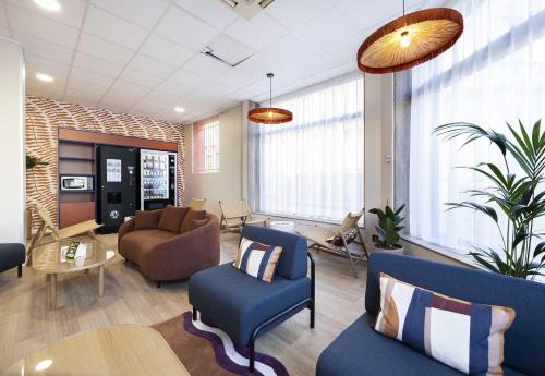 a lobby with blue chairs and a table and chairs at B&B HOTEL Perpignan Centre in Perpignan