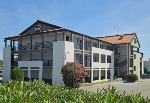 a large white building with a red roof at B&B HOTEL Avignon 1 in Le Pontet