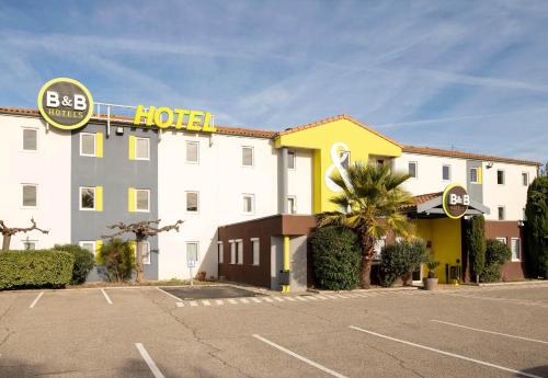 a hotel with a parking lot in front of it at B&B HOTEL Avignon 2 in Le Pontet