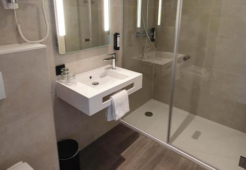 a bathroom with a white sink and a shower at B&B HOTEL Hasselt in Hasselt