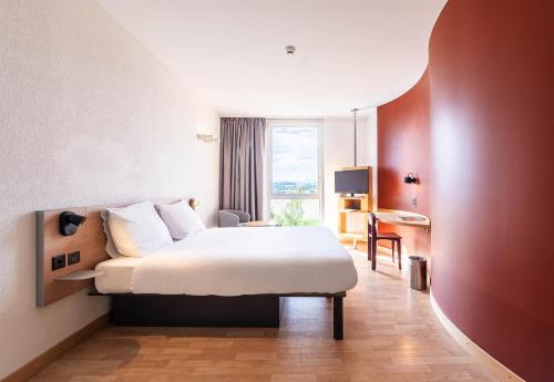 a hotel room with a bed and a window at B&B HOTEL Lully 3 Lakes in Estavayer-le-Lac