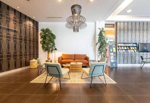 a lobby with a couch and chairs and a table at B&B HOTEL Lully 3 Lakes in Estavayer-le-Lac