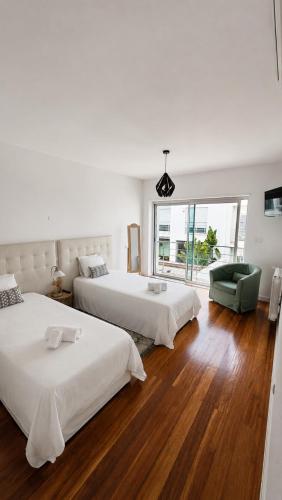 a bedroom with two beds and a green chair at Casa do Mar Oeiras in Oeiras