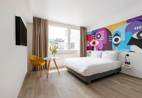 a hotel room with a bed and a painting on the wall at B&B HOTEL St Gallen in St. Gallen