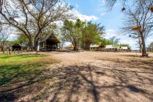 a large building with a group of trees in the background at Chobe River Campsite in Ngoma