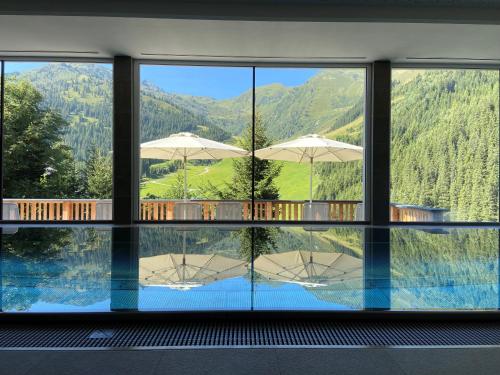 a room with a view of a pool and mountains at Hotel Zirbenhof in Hochfugen