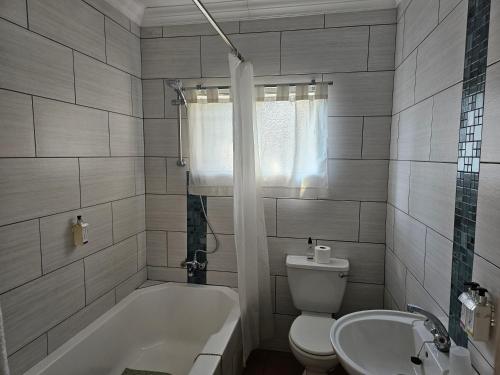 a bathroom with a tub and a toilet and a sink at PhysEQFiT Guesthouse in Centurion