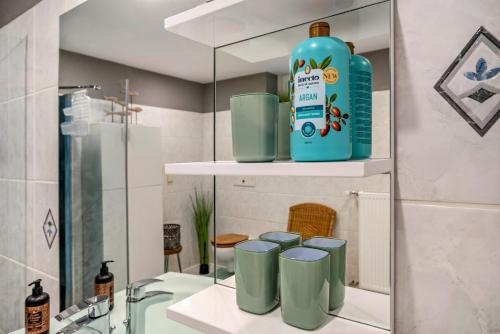 a bathroom with a bottle of detergent and four green cups at Eifelraum-Relaxwohnung mit Sauna in Oberbettingen