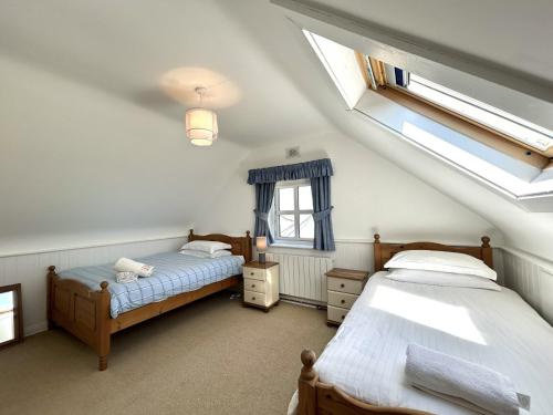 a attic bedroom with two beds and a window at 14 Leitirshask, Ballyconneely in Ballyconneely