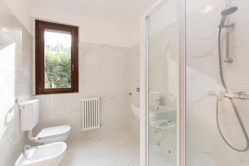 a white bathroom with a toilet and a shower at Residence Borgo Castello B1 Apartment in Argegno