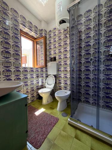 a bathroom with a toilet and a glass shower at La Vela Apartment in Stintino