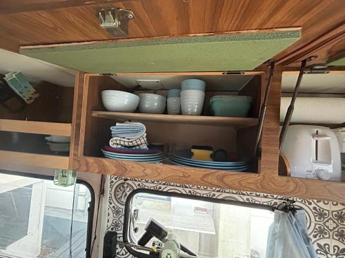 a cabinet in the back of an rv with dishes at Charmantes Oldtimer Wohnmobil in Aachen