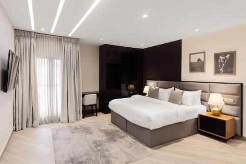a bedroom with a large white bed and a desk at Yellow Trumpet Iris Maitama in Abuja