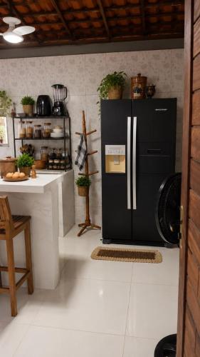 a kitchen with a black refrigerator and a counter at Chalé Canto do Rio in Santo Amaro