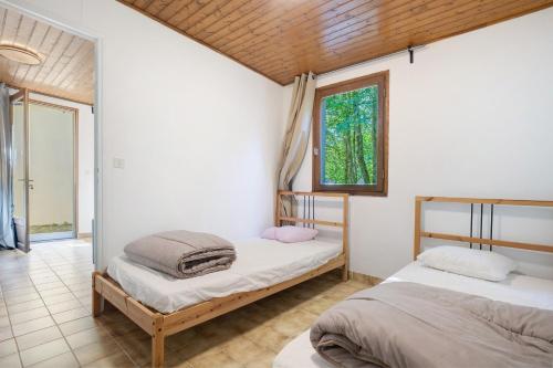 two beds in a room with a window at 7.Les rossignols option Clim-4 pers in Calviac