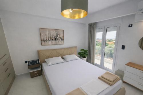 a bedroom with a large white bed and a window at Hanna's Villagio in Korinthos