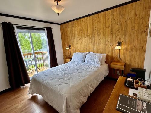 a bedroom with a bed and a desk and a window at Auberge Du Lac Malcom in Sayabec