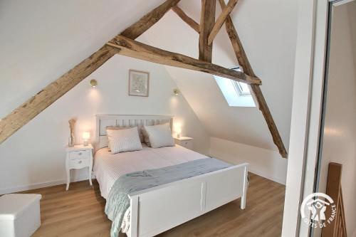 a bedroom with a white bed in a attic at Les pierres d'armor in Vildé-Guingalan