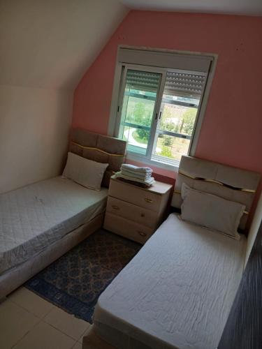 two beds in a small room with a window at maison Halima in Ifrane