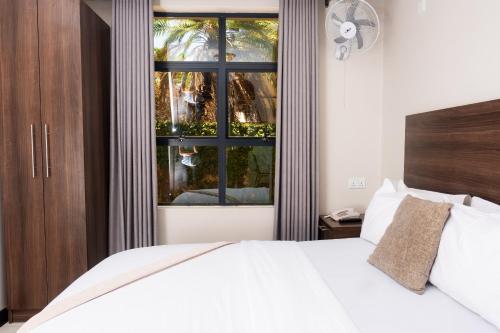 a bedroom with a white bed and a window at Purpose International Hotel Eastlea in Harare
