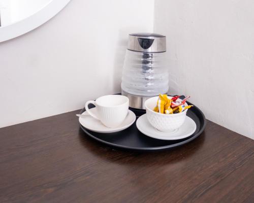 a black plate with two cups and a bowl of snacks at Purpose International Hotel Eastlea in Harare