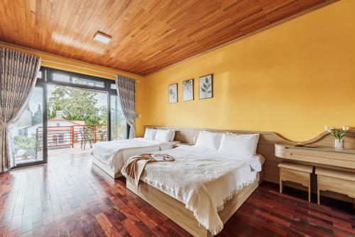 two beds in a room with yellow walls at AT House Dalat - The Pine Concept in Da Lat
