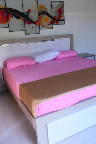 a bed with pink sheets and pillows on it at Madu Rivora Villa in Ambalangoda
