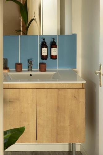 a bathroom sink with two bottles of whiskey on it at Hôtel Latécoère in Biscarrosse