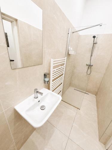 a white bathroom with a sink and a shower at City Apartment 1 in Vienna