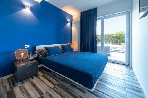 ein blaues Schlafzimmer mit einem Bett und einem großen Fenster in der Unterkunft Le Stanze e il Mare in Polignano a Mare