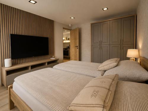 a bedroom with two beds and a flat screen tv at Wendell Apartman in Nyíregyháza