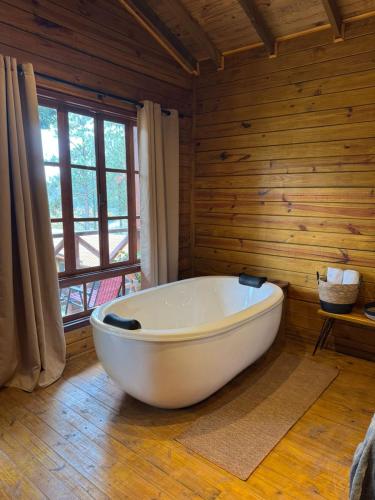 a white bath tub in a room with wooden walls at Cinque chalé in São Roque