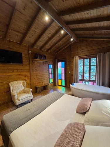 a bedroom with a bed and a tub in a room at Cinque chalé in São Roque