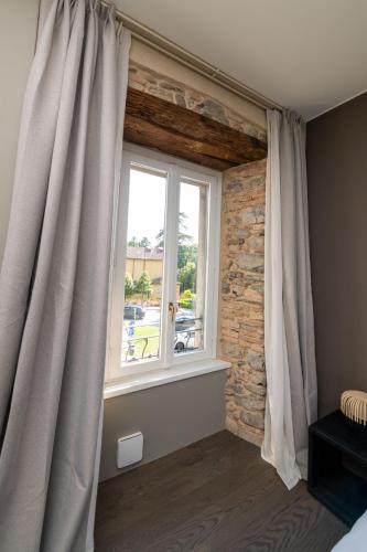 a window with curtains in a room with a brick wall at Albergo Canzo in Canzo