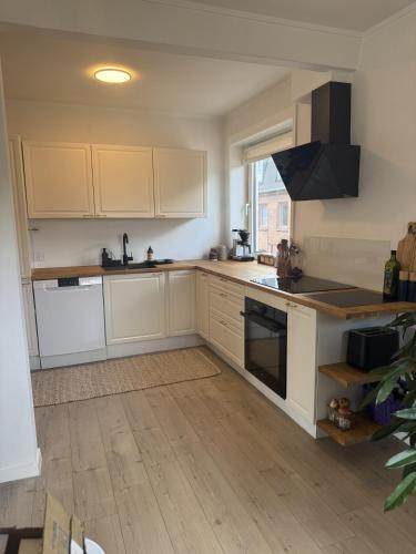 a kitchen with white cabinets and a stove top oven at Hygge Home Aalborg, Free Parking & 15 Min to City Centre in Nørresundby