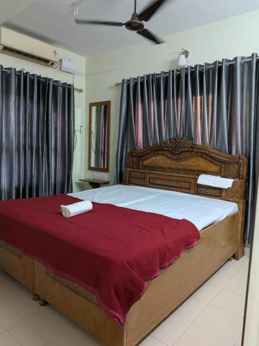 a bedroom with a large bed with a red blanket at walking distance from temble in Guruvāyūr