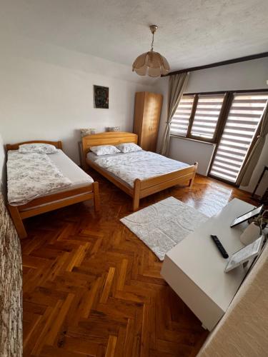 two beds in a room with wooden floors and windows at Apartments Aida in Bihać