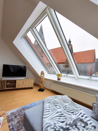 an attic living room with a large window at Traumblick Barth - Boddenblick, Tiefgarage & Aufzug in Barth