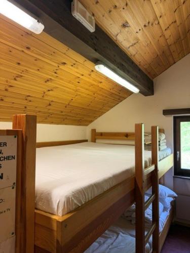 a bedroom with two bunk beds in a wooden ceiling at Capanna Tremorgio in Quinto