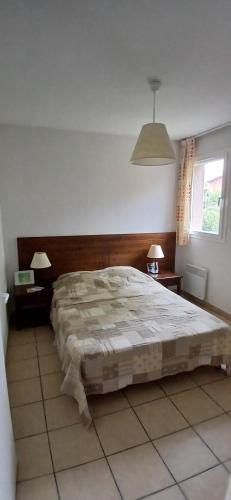 a bedroom with a large bed and two tables and a window at Beau séjour in Prayssac