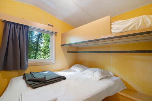 a small bedroom with a bed and a window at 21.Mobil-home option clim-5 pers in Calviac