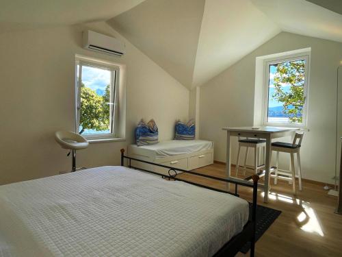a bedroom with a bed and a desk and two windows at Casa Caprice in Cannero Riviera