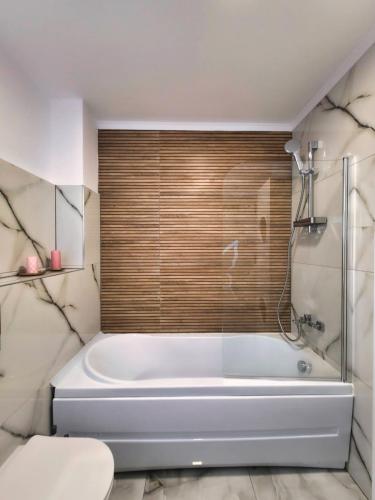 a white bath tub in a bathroom with a window at Skylark Apartments in Râmnicu Vâlcea