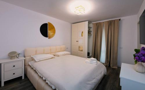 a bedroom with a white bed and a white dresser at Skylark Apartments in Râmnicu Vâlcea