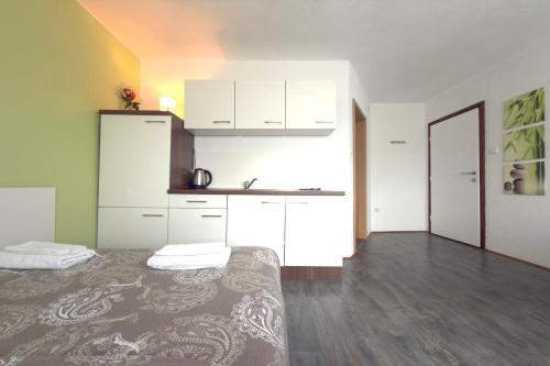 a room with a bed and a kitchen with white cabinets at ASGARD Guesthouse in Josipdol