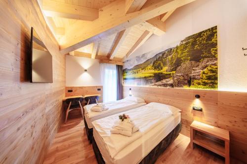 a bedroom with a bed with a painting on the wall at Hotel Cristallo in Andalo