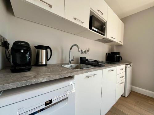 a kitchen with white cabinets and a sink at Hawthorn Stays in Maynooth