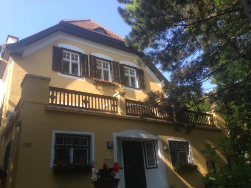 ein gelbes Haus mit Balkon darüber in der Unterkunft Exquisites Gartenapartment in eleganter Jugendstilvilla in Wien